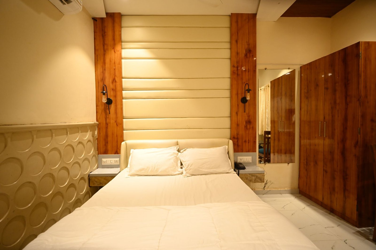 Deluxe bedroom with cream padded headboard and teak panels, beach resort in Gorai Mumbai