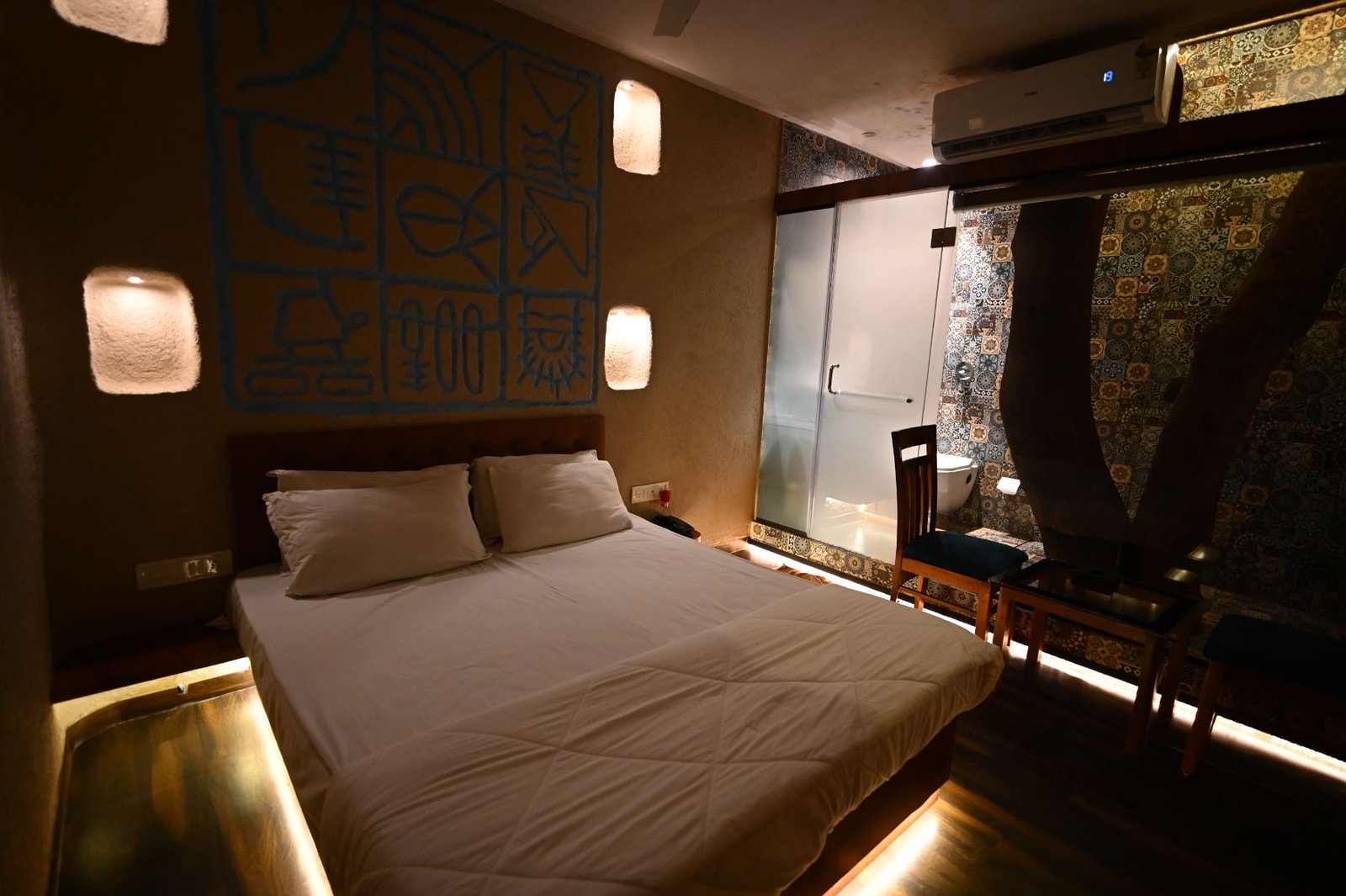 Nature's Vault room interior with ochre lime plaster walls and a blue relief mural, Gorai beach resort