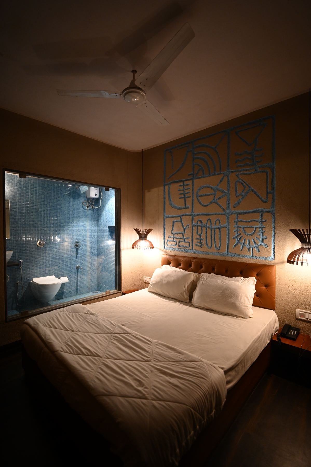 Semi Deluxe room interior with blue relief mural above the bed, beach resort in Gorai